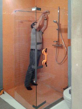 Szklarz montujący narożną kabinę prysznicową w Radzyminie